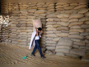A worker carries a sack of wheat for sifting at a grain mill on the outskirts of Ahmedabad