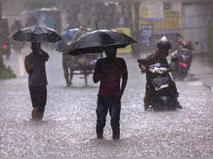 Kochi: Commuters wade through a waterlogged road during heavy rain in Kochi. (PT...