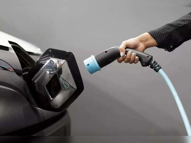 FILE PHOTO: A woman holds a cable to charge a Renault Kangoo ZE electric utility vehicle at a Renault dealership in Cagnes-Sur-Mer