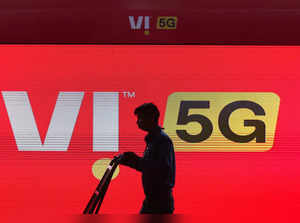 A man walks across the LED display board showing the logo of Vodafone-Idea at the ongoing India Mobile Congress 2022, at Pragati Maidan, in New Delhi