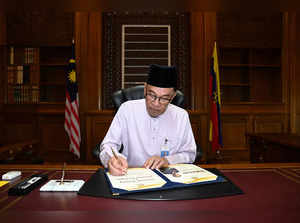 Malaysia's newly appointed Prime Minister Anwar Ibrahim signing a document at Putrajaya