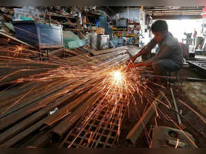 A worker grinds a metal gate inside a household furniture manufacturing factory in Ahmedabad