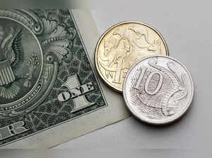 Photo illustration shows one dollar and 10 cents in Australian currency sitting atop a U.S. one dollar note in Sydney