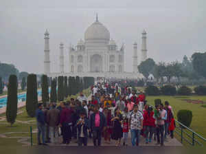 Agra: People visit Taj Mahal as it is covered by light fog on a winter evening, ...