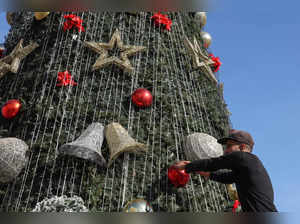 A worker places decorations on a Christmas tree