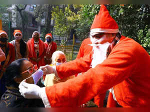 New Delhi: A man dressed as Santa Claus distributes masks to take precautionary measures for Covid-19 on the occasion of Christmas, in New Delhi on Sunday, Dec. 25, 2022. (Photo: IANS)