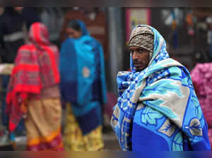 New Delhi: A labourer wrapped in a blanket stands at a market during a cold wint...