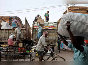 Labourers load consumer goods onto supply trucks at wholesale market in Kolkata