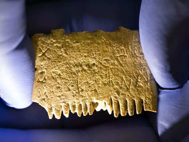 A 3,700-year-old ivory comb found in southern Israel bears an inscription that reads, “May this tusk root out the lice of the hair and the beard.”Credit...Menahem Kahana/Agence France-Presse — Getty Images