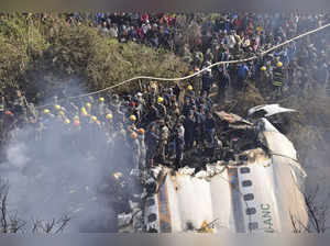 Nepalese rescue workers and civilians gather around the wreckage of a passenger ...