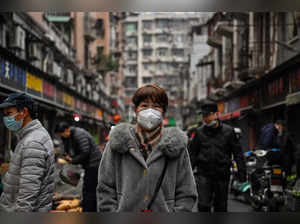People walk down a street next to a local market in Wuhan, in China's central Hubei province, on January 23, 2023. (Photo by Hector RETAMAL / AFP)