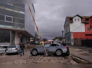 A pedestrian walks by cars on a damaged street after heavy rain in Kosovo, in Skenderaj on January 20, 2023. (Photo by Armend NIMANI / AFP)