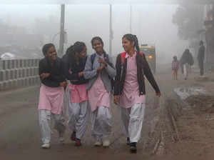 Gurugram: Students on their way to school amid dense fog during a cold winter mo...