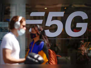 People walk past a 5G data network sign at a mobile phone store in Paris.