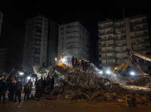 Rescue workers search for bodies and earthquake survivors on a collapsed buildin...