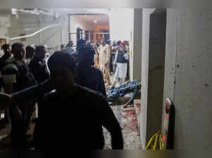 Security officials gather near a body in the aftermath of an attack on a police station in Karachi