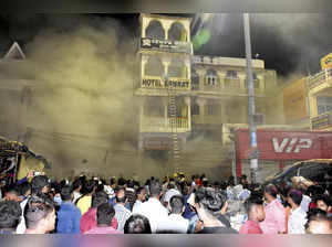 Puri: People gather near a hotel where a fire broke out at Grand Road, in Puri. ...