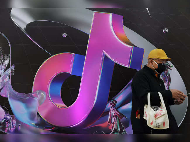Man stands near a giant sign of Chinese company ByteDance's app TikTok, known locally as Douyin, during China Fashion Week, in Beijing