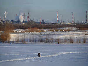 A fisherman walks near an oil refinery in Omsk