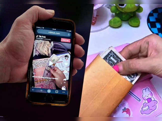 This illustration picture shows the “cash stuffing” TikTok trend, videos where people put cash in envelopes as a budgeting method, displayed on a smartphone in Washington, DC, on March 15, 2023.  Manicured fingers meticulously place cash in transparent envelopes marked "food," "gas" and other categories, demonstrating in a TikTok video a retro technique for controlling what you spend that is newly popular with some money-conscious Americans. Returning to cash to control spending may be old fashioned, but in an era of high inflation, a growing number of consumers finds that it works. (Photo by OLIVIER DOULIERY / AFP)