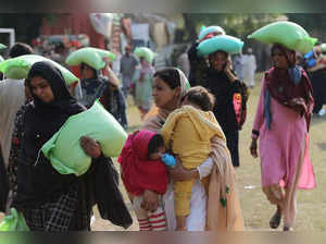 People leave after collecting free bags of flour from a government distribution point in Multan on March 22, 2023, following an announcement by Pakistan’s Prime Minister Shehbaz Sharif to provide free flour to people in need ahead of the Muslim holy fasting month of Ramadan.  (Photo by Shahid Saeed MIRZA / AFP)