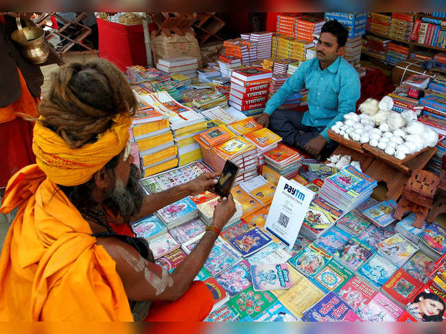FILE PHOTO: A Sadhu or a Hindu holy man pays the vendor through Paytm, a digital wallet company, after buying a book during the annual religious festival of Magh Mela in Allahabad