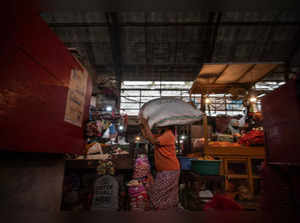 A woman labourer carries goods over her head at a traditional market in Surabaya on April 5, 2023. (Photo by JUNI KRISWANTO / AFP)