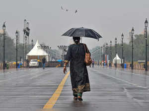 New Delhi: A tourist covers herself with an umbrella as she visits the newly-nam...