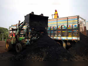 Workers unload coal from a supply truck at a yard on the outskirts of Ahmedabad