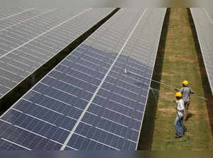 FILE PHOTO: Workers clean photovoltaic panels inside a solar power plant in Gujarat