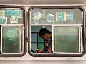 A man looks into his phone as he travels in an intercity bus service in New Delhi