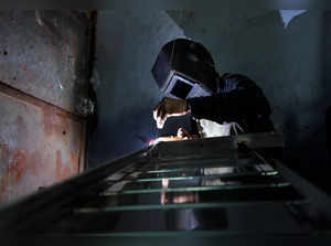 A worker welds steel pipes to make a counter at a steel furniture manufacturing unit in Ahmedabad