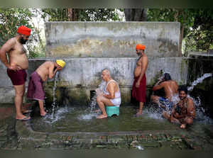 Amritsar, May 14 (ANI): People cool off by taking a bath at a common bathing pla...