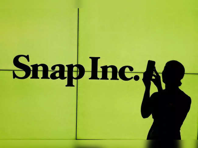 FILE PHOTO: FILE PHOTO: A woman stands in front of the logo of Snap Inc. on the floor of the New York Stock Exchange in New York City
