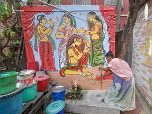 Kolkata: A women collects water from a tap for her daily chores near a painted w...