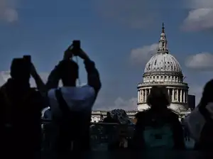 Pedestrians take pictures with their phone as they walk across the Millenium Bridge with Saint Paul's cathedral on the background, in London, on April 17, 2023. (Photo by Ben Stansall / AFP)