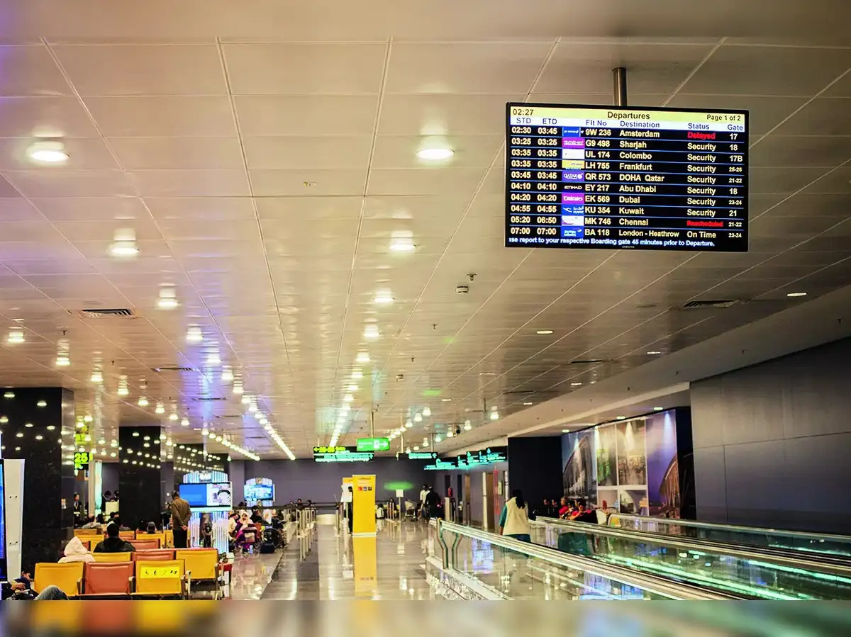 Many travelers are seated and waiting inside Hong Kong International Airport as a departure board displays several flights, with some flights marked as security or rescheduled, amid signs of a typhoon impacting the airport on September 22, 2025.