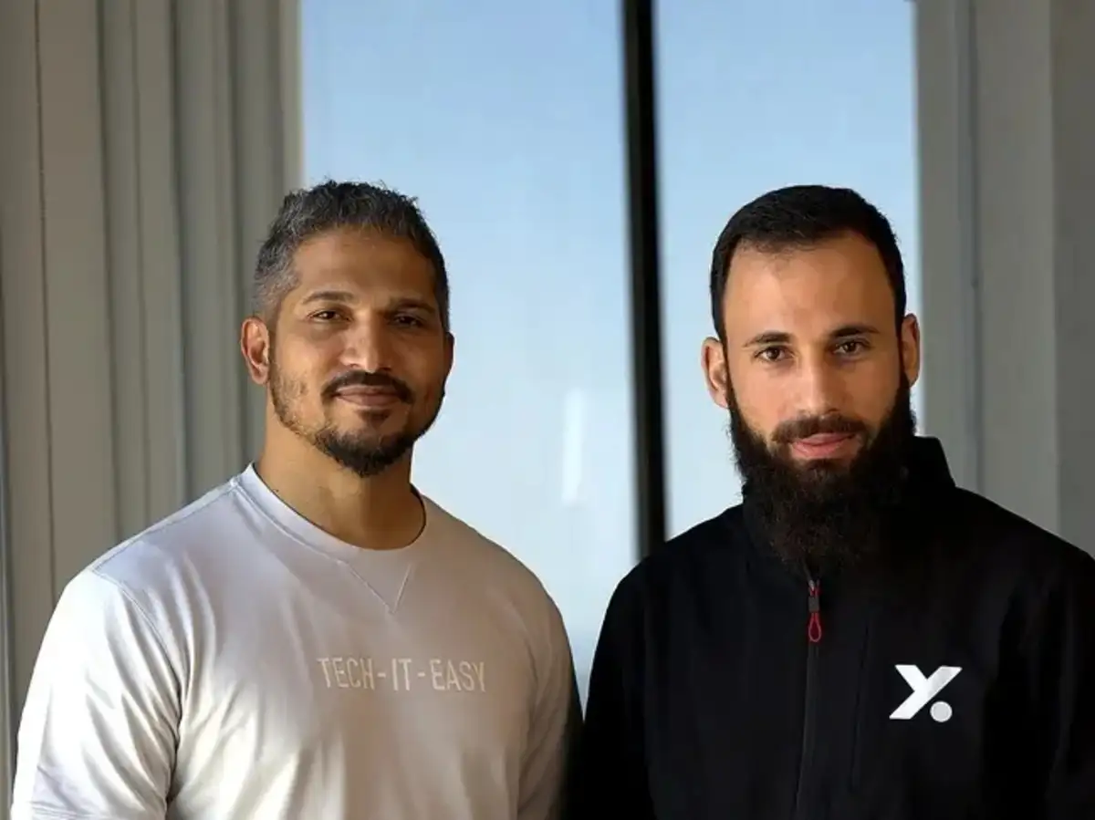 Two company logos, CNTXT AI and Actualize, merging or shaking hands, overlaid on a digital representation of voice waveforms and a map of the GCC.
