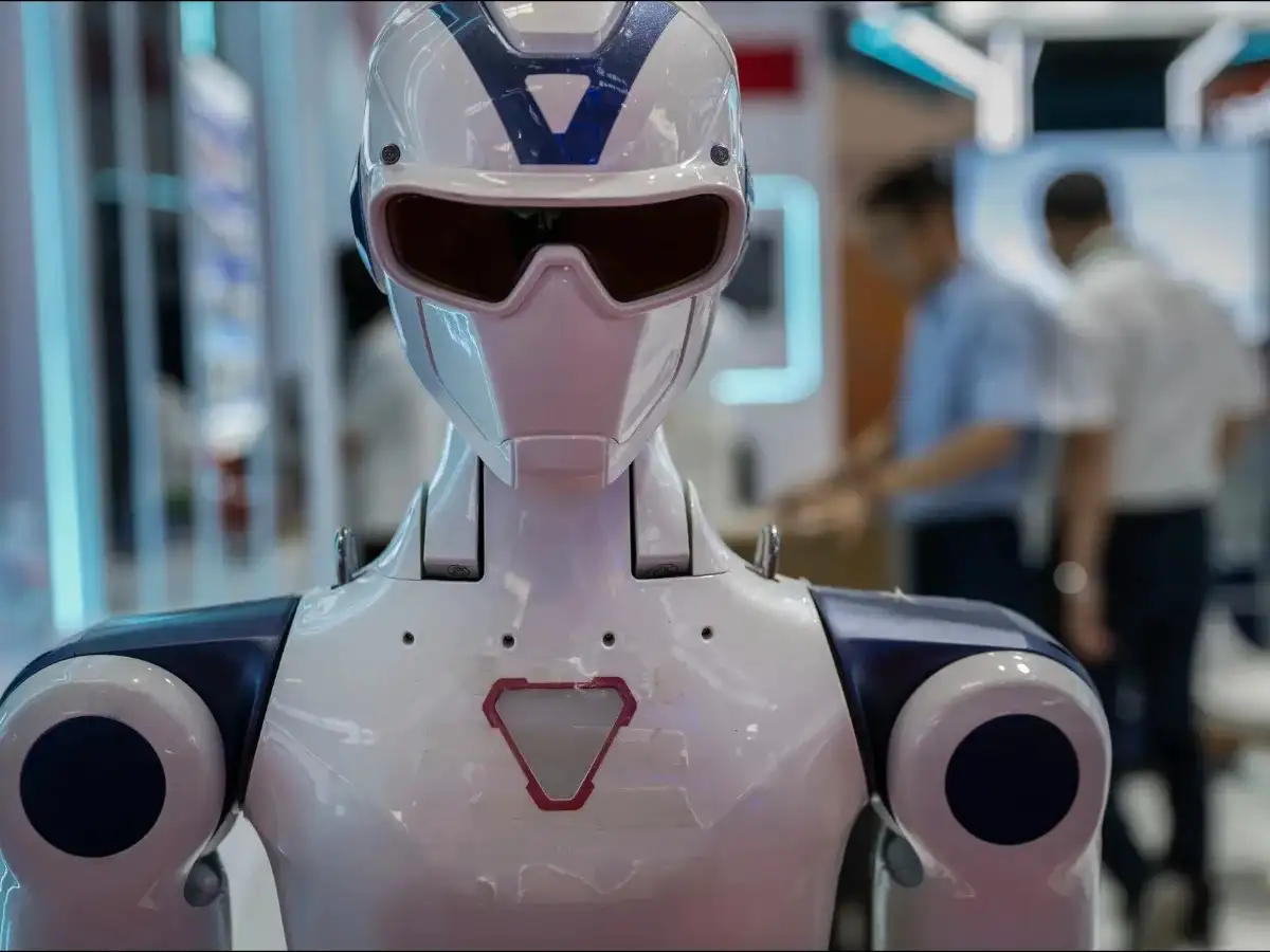 A robotic dog-style quadruped walking on a reflective floor in a modern office setting