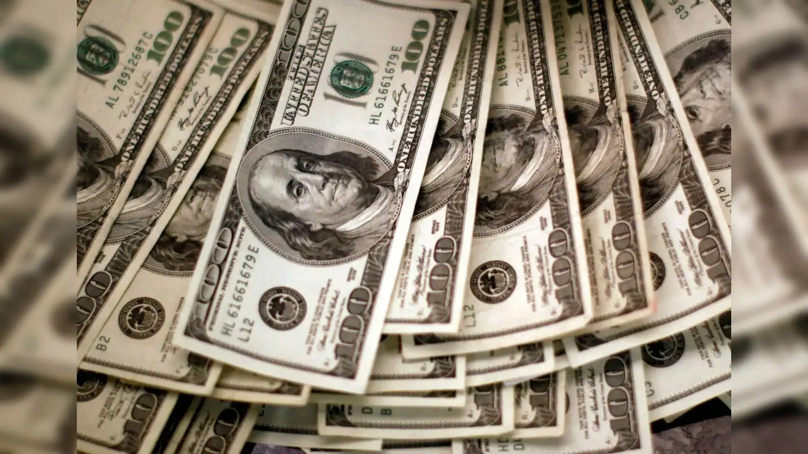Multiple hundred-dollar bills are fanned out, with some overlapping, representing significant financial dealings related to global debt and investor shifts in US Treasuries, Japane